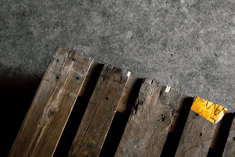 Wood pallet on concrete ground with yellow sticker.